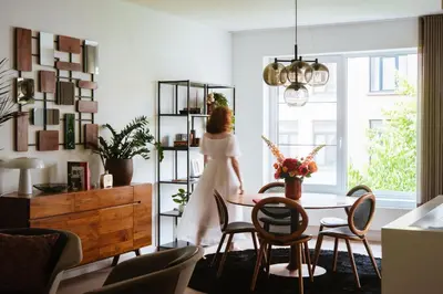 a woman walking through a living room with a table and chairs at La Petite Foret Design Flat in Antwerp City in Antwerp