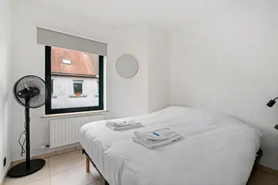 a bedroom with a bed with white sheets and a window at Comfort aan stadsrand Gent, vlakbij Natuurgebied in Ghent