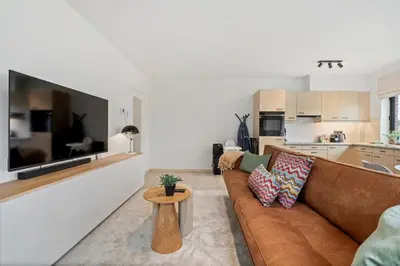 a living room with a brown couch and a table at Comfort aan stadsrand Gent, vlakbij Natuurgebied in Ghent