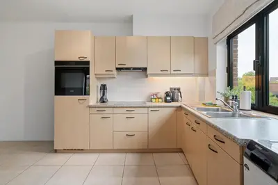 a kitchen with wooden cabinets and a sink at Comfort aan stadsrand Gent, vlakbij Natuurgebied in Ghent