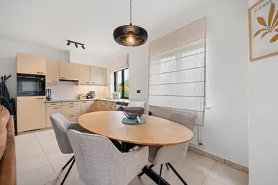 a kitchen and dining room with a wooden table and chairs at Comfort aan stadsrand Gent, vlakbij Natuurgebied in Ghent