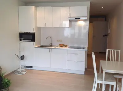 a kitchen with white cabinets and a table and a dining room at Hyppolite Metdepenningenstraat G in Ghent