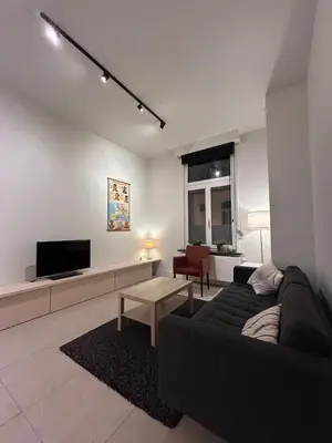 a living room with a black couch and a tv at Studio Tzawel in Ghent
