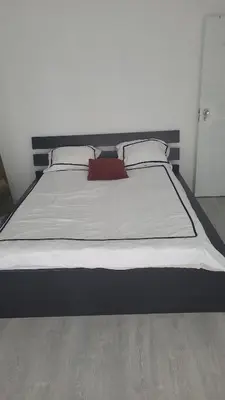 a large bed in a bedroom with white sheets and pillows at Une Maison chaleureuse in Lebbeke