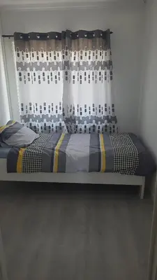 a bed in a room with a window with a curtain at Une Maison chaleureuse in Lebbeke