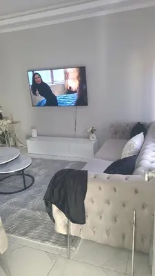 a living room with a couch and a tv on the wall at Une Maison chaleureuse in Lebbeke