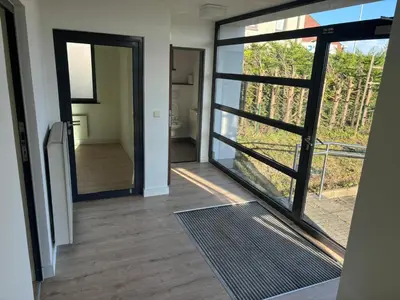 a hallway with a sliding glass door and a bathroom at Stay Here in Erpe-Mere
