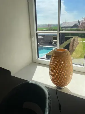 a vase sitting on a table next to a window at La maison de Nikolas in Oosterzele