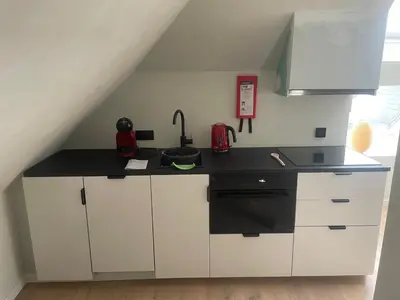 a kitchen with white cabinets and a black counter top at La maison de Nikolas in Oosterzele
