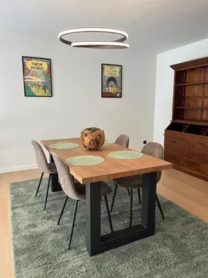 a dining room with a wooden table and chairs at Appartement ' Tintin Travels' in Geel