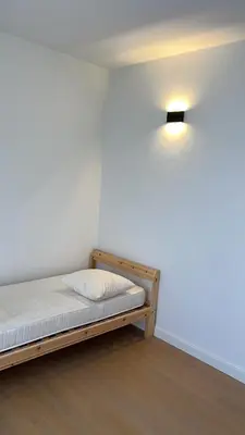 a bed in a room with a light on the wall at Appartement ' Tintin Travels' in Geel