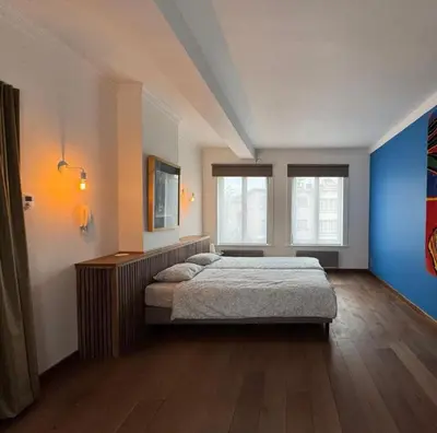 a bedroom with a large bed and two windows at Sint-Catharina in Lier