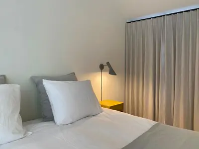 a bedroom with a bed with white sheets and a lamp at Hyggehus Tervuren in Tervuren