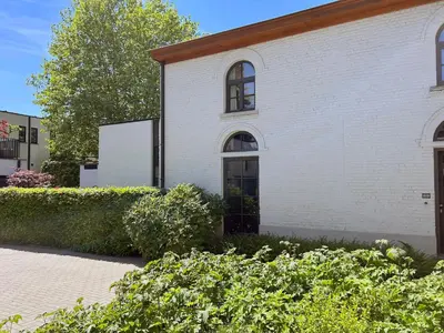 a white building with a black door and some bushes at Hyggehus Tervuren in Tervuren