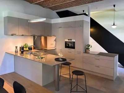 a kitchen with white cabinets and a island with stools at Hyggehus Tervuren in Tervuren