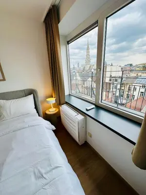 a bedroom with a bed and a large window at Grand Place View - 2bd - Exclusive Apartment in Brussels