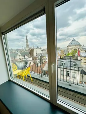 a window with a yellow bench looking out at a city at Grand Place View - 2bd - Exclusive Apartment in Brussels