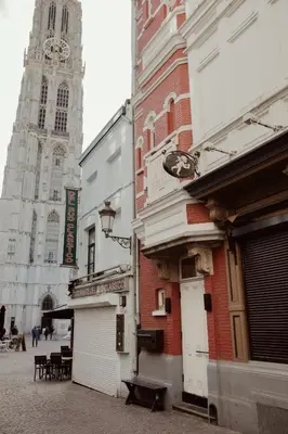 a building on a street with a clock tower at A Place Antwerp - Boutique Suites & Flats - Oude Koornmarkt 1 in Antwerp