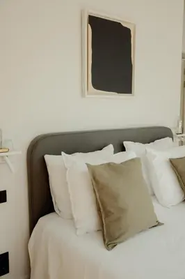 a bed with white pillows and a picture on the wall at A Place Antwerp - Boutique Suites & Flats - Oude Koornmarkt 1 in Antwerp