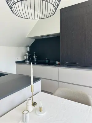 a kitchen with a white table and a black cabinet at Dakappartement V, 2de verdiep TML in Willebroek