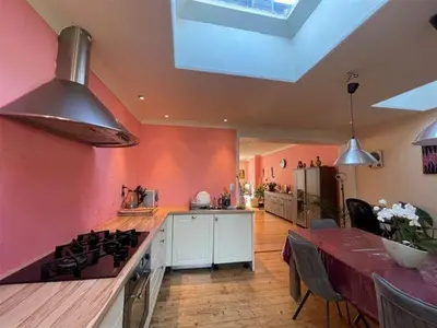 a kitchen with pink walls and a stove and a table at Nyumbani Stays in Boom