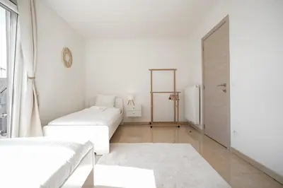 a white room with two beds and a door at Penthouse with a Neo-Gothic Parish church view in Ghent