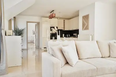 a white living room with a white couch and a kitchen at Penthouse with a Neo-Gothic Parish church view in Ghent
