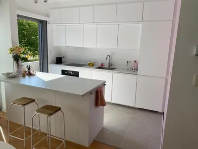 a kitchen with white cabinets and a counter with stools at Modern & Cozy Apartment near Tomorrowland- Sleeps 4 in Edegem