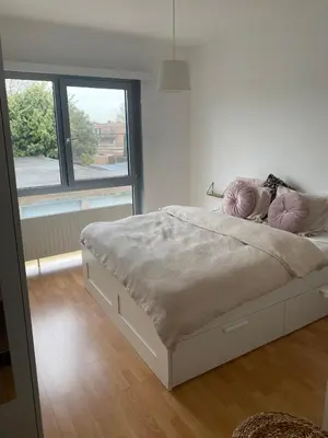 a white bed with pink pillows in a bedroom at Modern & Cozy Apartment near Tomorrowland- Sleeps 4 in Edegem