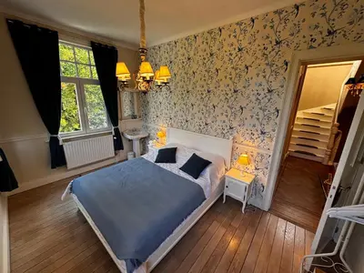 a bedroom with a bed and floral wallpaper at Le Manoir des Etangs in Etbos