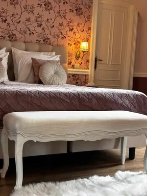 a bedroom with a large bed with a white bench at Le Manoir des Etangs in Etbos