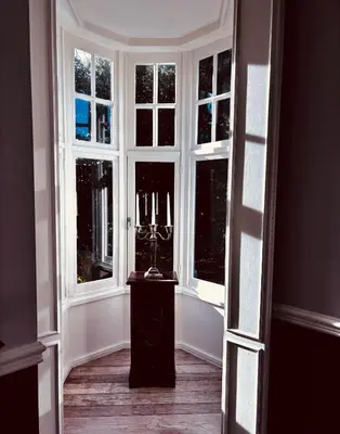 a hallway with windows and a statue in front of it at Le Manoir des Etangs in Etbos