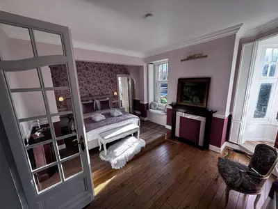 a bedroom with a bed and a chair and a door at Le Manoir des Etangs in Etbos