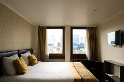 a hotel room with a bed and two windows at The Helmet Hotel in Brussels