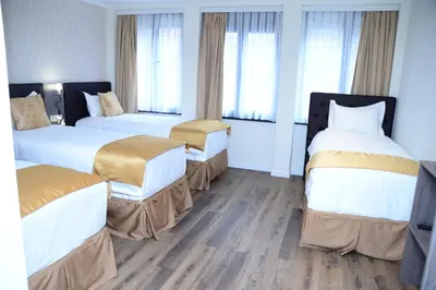 a hotel room with two beds and two windows at The Helmet Hotel in Brussels