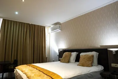 a hotel room with a bed with white sheets and gold pillows at The Helmet Hotel in Brussels