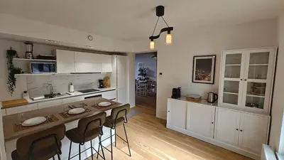 a kitchen with white cabinets and a bar with stools at Highgarden - warm & cozy in Brussels