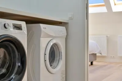 a washer and dryer in a room with a bed at Stylish 1BR close to KMSKA in Antwerp