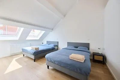 two beds in a bedroom with white walls and wood floors at Toison d'Or in Brussels