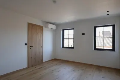 an empty room with a door and two windows at luxurious home in Oud-Turnhout