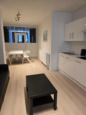 an empty living room with a table and a kitchen at Cityhome in Brussels