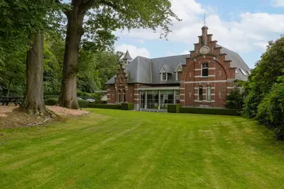 a large brick building with a clock tower on it at Villa Gentbos - currently 15beds 3bathrooms - from june 2026 up to 21beds 6bathrooms in Pataterhoek
