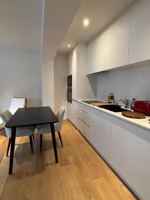 a kitchen with white cabinets and a table and chairs at Studio Vleurgat in Brussels