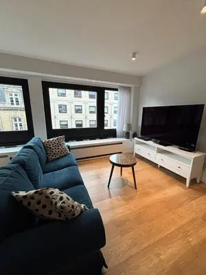 a living room with a blue couch and a flat screen tv at Studio Vleurgat in Brussels