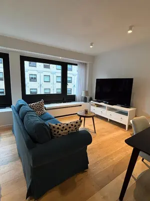 a living room with a blue couch and a flat screen tv at Studio Vleurgat in Brussels