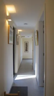 a hallway with white walls and a long hallway with lights at B&B Zoersel in Zoersel