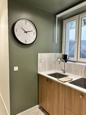 a clock on the wall of a kitchen with a sink at New studio centre in Brussels