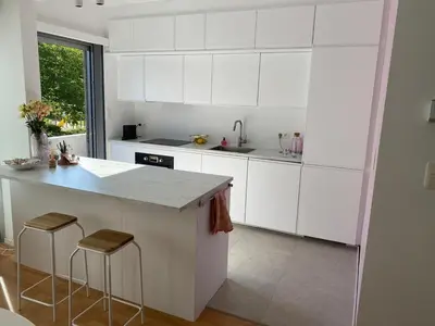 a white kitchen with a counter and stools in it at Perfect for Tomorrowland in Edegem