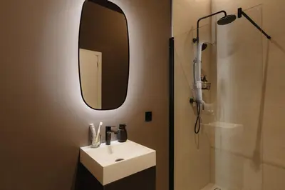 a bathroom with a sink and a mirror and a shower at Raibu Antwerp by StayC in Antwerp