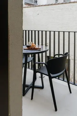 a table and a chair sitting on a balcony at Raibu Antwerp by StayC in Antwerp